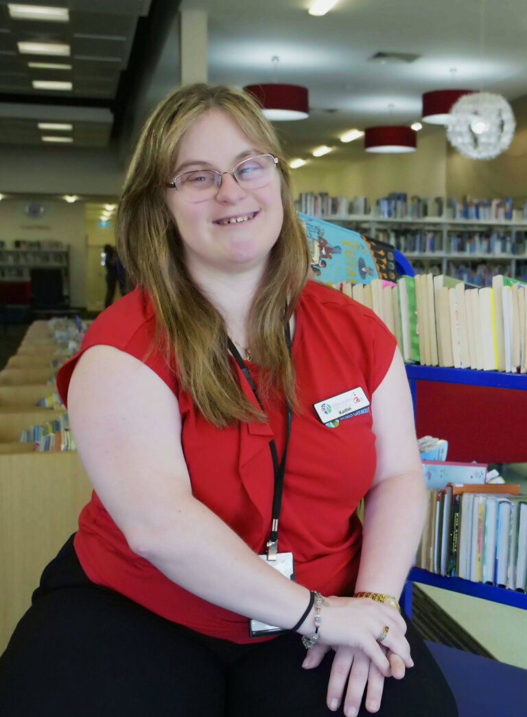 Kailtin sitting in the Library smiling at the camera