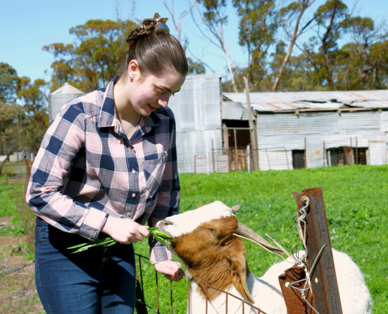 Sarah on her farm feeding a goat