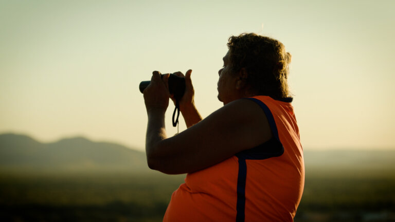 Maryanne, in action, taking an photo at sunset on the land.