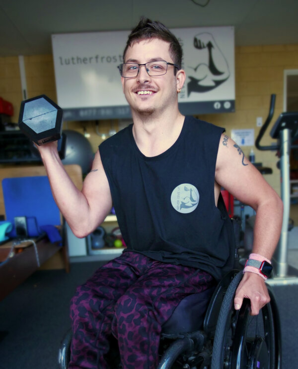 Luther holding a dumbbell in his garage gym. 