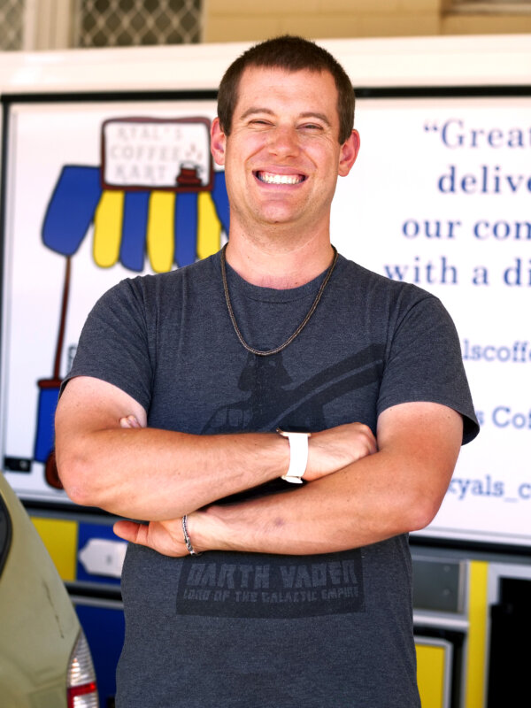 Kyal smiling at his coffee cart business.